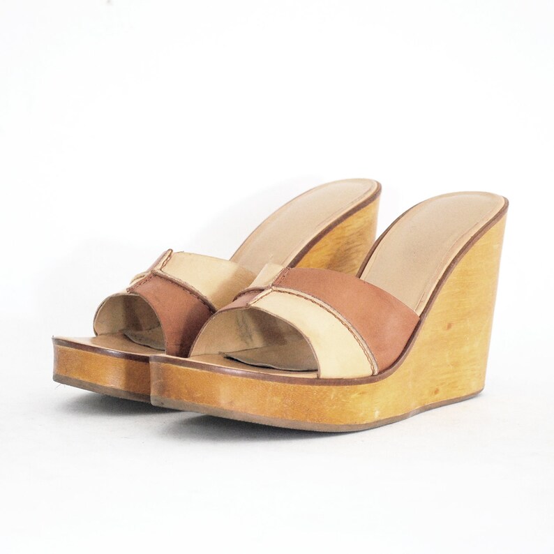 May include: A pair of brown and beige platform sandals with a wooden wedge heel.
