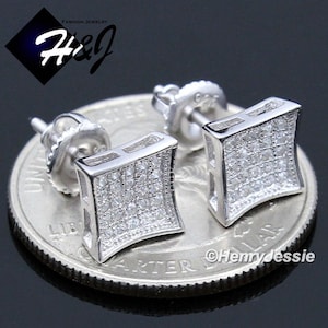 May include: Silver-toned square stud earrings with a pave of small, clear stones. The earrings are set on a silver post and are displayed on a coin. The image includes the text "Fashion Jewelry H&J" and the copyright "©Henryjessie".