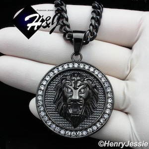 May include: Black chain necklace with a round pendant featuring a lion's head with clear rhinestones around the edge.