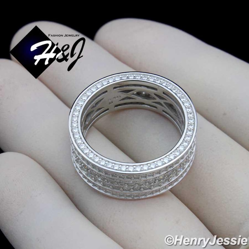 May include: A silver-toned ring with multiple rows of small, clear gemstones. The ring has a wide band design and is set against a light background. The ring is labeled "H&J Fashion Jewelry" and "Henry Jessie".