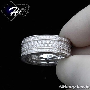 May include: A silver ring with multiple rows of small, clear gemstones. The ring is held by a gloved hand. The ring has the text "S-925" engraved on it. The image also includes the text "Fashion Jewelry" and the brand name "H&J".