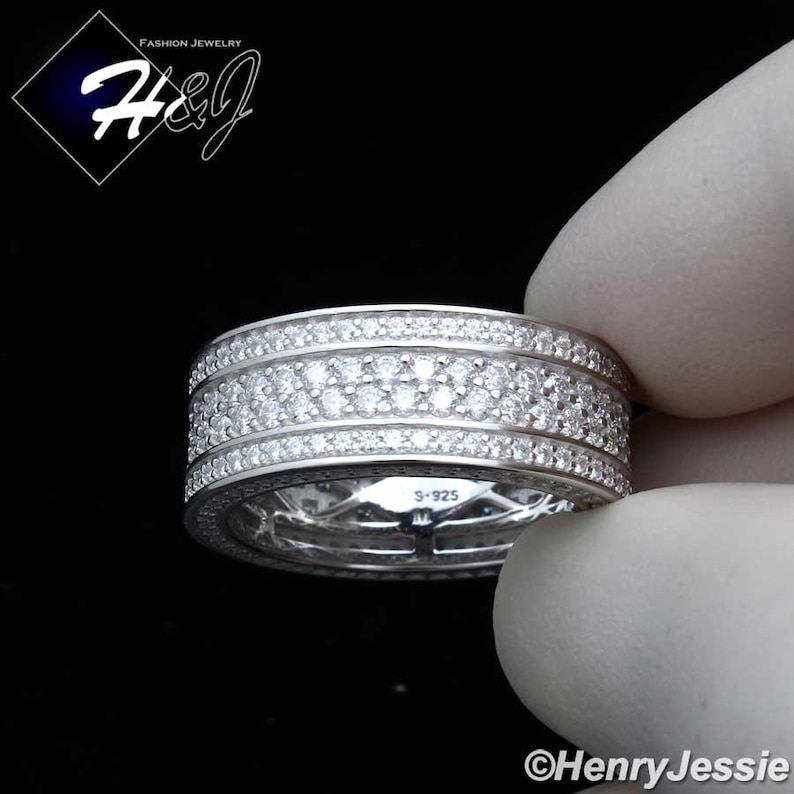 May include: A silver ring with multiple rows of small, clear gemstones. The ring is held by a gloved hand. The ring has the text "S-925" engraved on it. The image also includes the text "Fashion Jewelry" and the brand name "H&J".