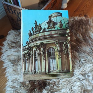 Könnte beinhalten: Handgefertigtes Holzschild mit dem Text "Welcome to our home" in handschriftlichem Stil. Das Schild ist weiß lackiert mit schwarzer Schrift und einem Used-Look, geeignet für den Innen- und Außenbereich.