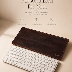Può includere: Una tastiera bianca con un tappetino da scrivania in pelle marrone. Il tappetino ha le iniziali "A M" incise. Il testo "Personalizzato per te" e "Incidi le tue iniziali. Rendilo davvero tuo" sono in alto.