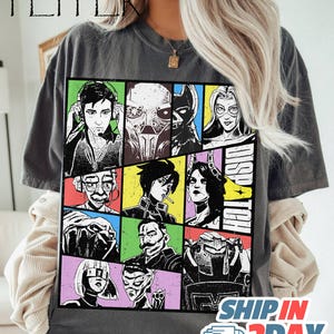 May include: Dark gray t-shirt featuring a grid of comic book-style character portraits in various colors. The word "DISPATCH" is vertically printed on the right side. The shirt has the text "SHIP IN 2DAY" at the bottom.