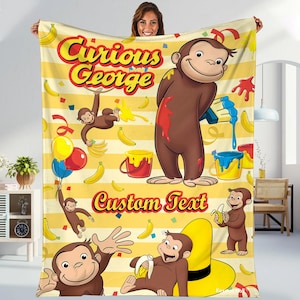 May include: A yellow blanket featuring Curious George illustrations with bananas, paint buckets, and balloons. The blanket has the text "Curious George" and "Custom Text" in a playful font.
