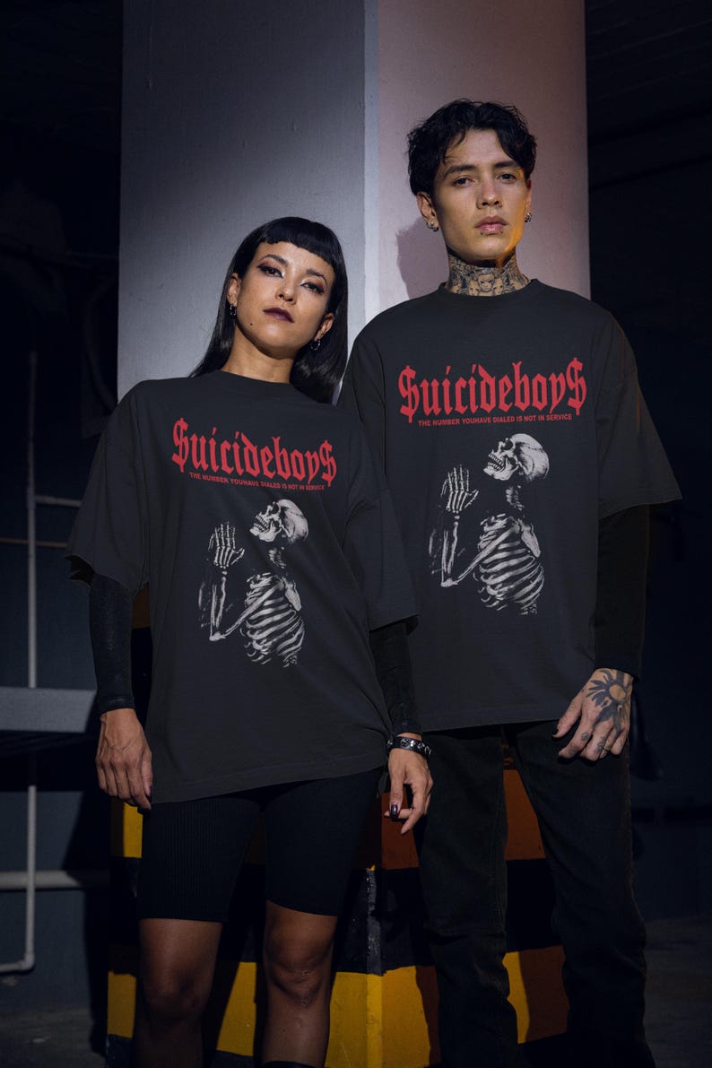 May include: Black t-shirts with the text "Suicideboys" in red gothic font. The shirts feature a skeleton graphic with praying hands. The phrase "THE NUMBER YOU HAVE DIALED IS NOT IN SERVICE" is printed below the logo.