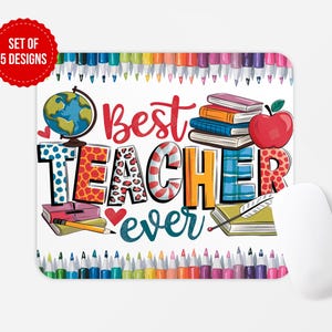 Könnte beinhalten: Ein weißes Mauspad mit einem bunten Design mit den Worten "Bester Lehrer aller Zeiten". Das Design beinhaltet einen Globus, Bücher, eine Feder und einen roten Apfel. Die Unterseite des Mauspads hat eine Reihe bunter Stifte.