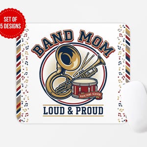Może przedstawiać: Prostokątna podkładka pod mysz z grafiką przedstawiającą tubę, trąbkę i bęben. Tekst głosi BAND MOM, MARCHING SEASON oraz LOUD & PROUD. Wzór zawiera nuty muzyczne oraz czerwono-biało-niebieską obwódkę w paski. Obok leży biała mysz komputerowa.