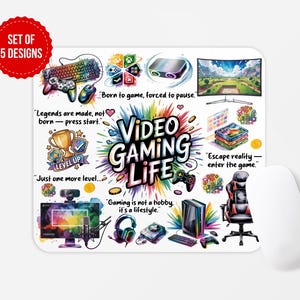 May include: A white rectangular mousepad with a colorful "Video Gaming Life" design. The design includes gaming-related illustrations, text, and a red circle that says "SET OF 5 DESIGNS". A white computer mouse is on the right.