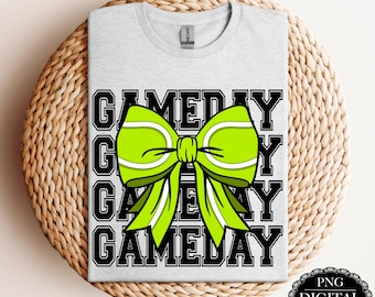May include: A gray t-shirt with the text "GAMEDAY" repeated four times in black. A green bow with white stripes is centered on the shirt.