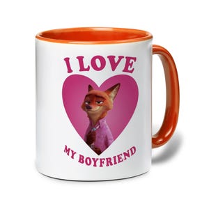 Op de afbeelding: Witte keramische mok met een oranje binnenkant en handvat. De mok heeft de tekst "I LOVE MY BOYFRIEND" in roze, met een cartoon vos karakter in een roze hart.