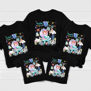Peut inclure: Cinq t-shirts noirs avec un motif repr&eacute;sentant une sir&egrave;ne, un homme et des cr&eacute;atures marines entour&eacute;s de d&eacute;corations de f&ecirc;te, de ballons et de cadeaux. Chaque t-shirt porte le chiffre 2 et une &eacute;tiquette : Daddy, Mommy, Brother, Sister ou Cindy.