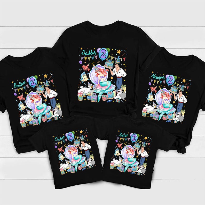Peut inclure: Cinq t-shirts noirs avec un motif repr&eacute;sentant une sir&egrave;ne, un homme et des cr&eacute;atures marines entour&eacute;s de d&eacute;corations de f&ecirc;te, de ballons et de cadeaux. Chaque t-shirt porte le chiffre 2 et une &eacute;tiquette : Daddy, Mommy, Brother, Sister ou Cindy.