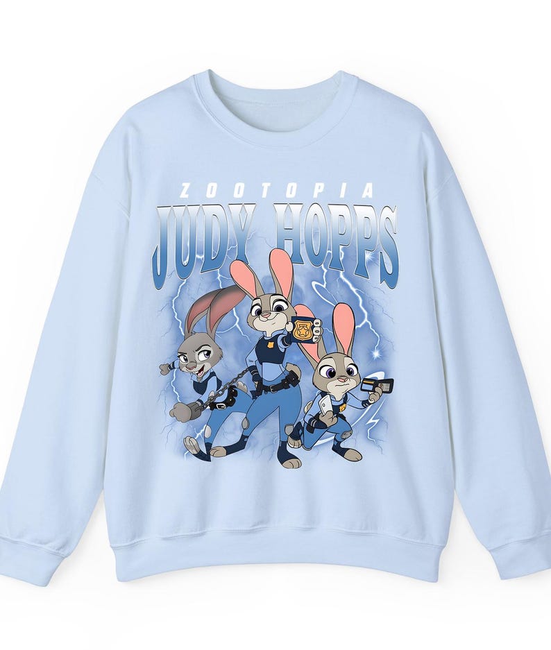 May include: Light blue sweatshirt featuring the text "ZOOTOPIA JUDY HOPPS" above a graphic of three cartoon rabbits in police uniforms. The rabbits are set against a backdrop of blue lightning bolts.