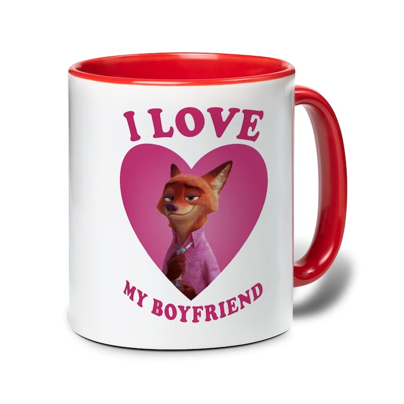 Op de afbeelding: Witte keramische mok met een rode binnenkant en handvat. De mok heeft een cartoon vos karakter in een roze hart, met de tekst "I LOVE MY BOYFRIEND" in roze letters.