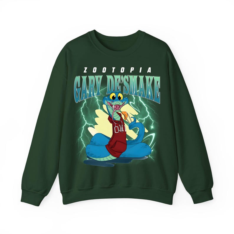 May include: Dark green sweatshirt featuring a cartoon snake character from Zootopia, named Gary De'Smake. The snake is blue with a red hoodie and is set against a background of lightning bolts. The word "Zootopia" and "Gary De'Smake" are printed on the sweatshirt.