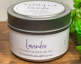Puede incluir: Una lata de vela redonda de metal plateado con una etiqueta blanca. La tapa dice INDULGE Lavender 100% SOY HANDPOURED 3.5 OZ. La etiqueta lateral dice Lavender HANDPOURED IN NC EnchantedStudios@Etsy.com 100% SOY 4 OZ.