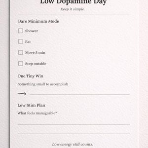 May include: A white paper with the text "Low Dopamine Day" and the phrase "Keep it simple." Checkboxes are listed under "Bare Minimum Mode" and "One Tiny Win." The phrase "Low energy still counts" is at the bottom.