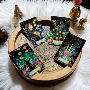 May include: Four tarot cards on a wooden tray with a circular design. The cards are from the 'Mystic Mondays' deck and feature illustrations of people and symbols. The cards are: 5 of Pentacles, 8 of Pentacles, 3 of Swords, and 6 of Pentacles.
