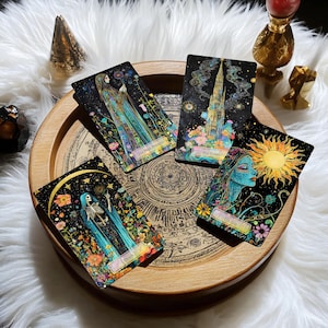 May include: Five tarot cards on a wooden tray with a black background and colourful floral designs. The cards are "The High Priestess", "The Tower", "The Sun", "Death", and "The World".