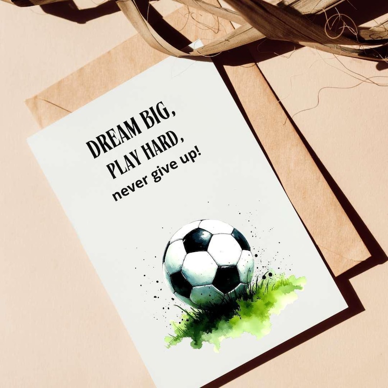 May include: A white card with black text that reads "Dream Big, Play Hard, never give up!" and a watercolor illustration of a soccer ball on green grass.
