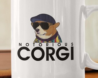 Puede incluir: Taza de cerámica blanca con una ilustración en blanco y negro de un corgi con gafas de sol y un sombrero. El texto "Notorious Corgi" está impreso en negro debajo de la ilustración.