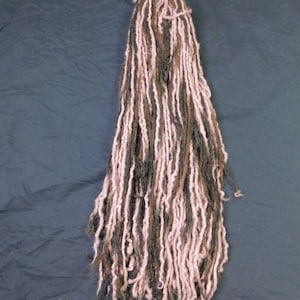 May include: A bundle of long, brown and pink yarn dreadlocks.