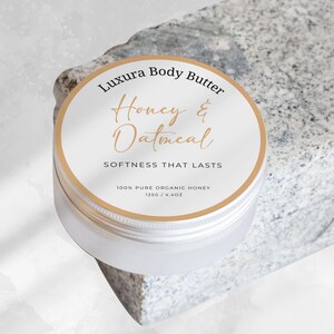 May include: A white jar of Luxura Body Butter with a gold lid and label. The label says "Honey & Oatmeal" and "Softness That Lasts". It also says "100% Pure Organic Honey 125g / 4.4oz".