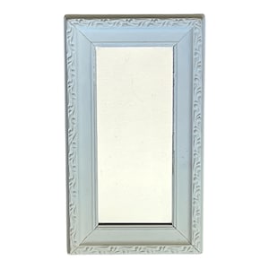 May include: A rectangular wall mirror featuring a light blue frame with a decorative embossed leaf pattern along the border. The mirror has a smooth, reflective glass surface centered within the frame, which has beveled edges leading to the glass.