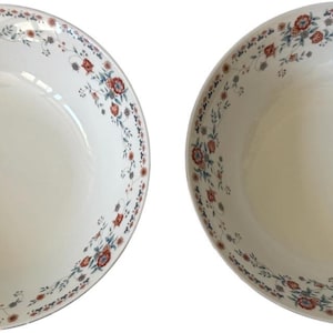 May include: Two round white ceramic bowls featuring a delicate floral pattern along the inner rim. The design consists of small red and orange flowers with green leaves and thin, winding brown vines arranged in a continuous circular border.