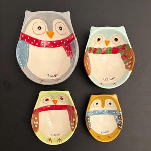 Può includere: Set di quattro tazze da misurare in ceramica a forma di gufo in blu, verde, giallo e grigio. Ogni tazza ha una dimensione diversa: 1 tazza, 1/2 tazza, 1/3 tazza e 1/4 tazza.