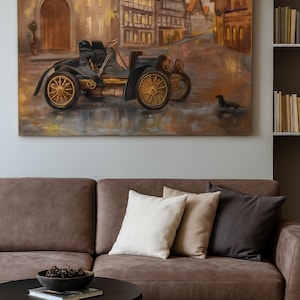 May include: Oil painting of a vintage black car with gold wheels on a cobbled street. The artwork depicts a European town scene with buildings and a small dog. The painting hangs above a brown sofa with cushions.