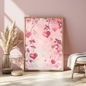 Könnte beinhalten: Ein Aquarellbild von rosa und roten Herzen, die an Ranken an einem rosa Hintergrund hängen. Die Herzen sind in verschiedenen Größen und Formen, und die Ranken sind mit Blättern verwoben.