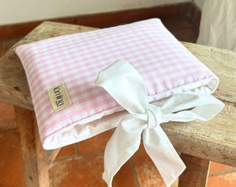 May include: A pink and white gingham pillow with a white bow. The pillow has a label that says "timina" on it.