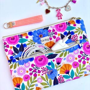 May include: A floral print zippered pouch with a white background, featuring blue, pink, and orange flowers. A matching keychain and a charm bracelet are also visible. The pouch contains a white charger and cable.