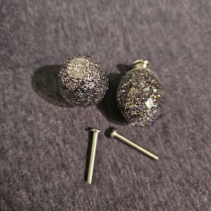May include: Two silver and clear glass cabinet knobs with a glittery finish and two silver screws.