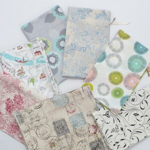 May include: Assortment of fabric pouches with various patterns, including floral, geometric, and vintage designs. The pouches are made of cotton and have zipper closures.