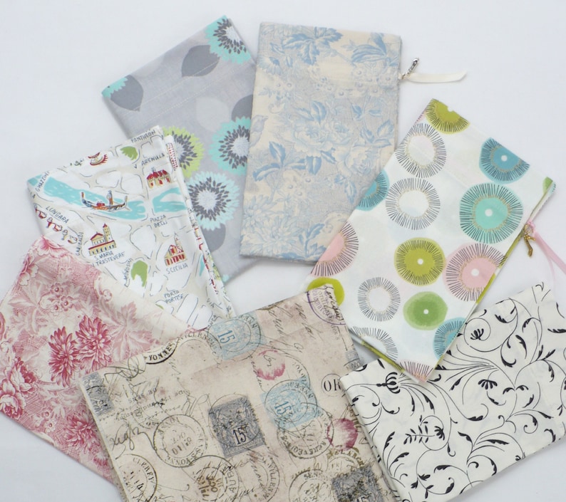 May include: Assortment of fabric pouches with various patterns, including floral, geometric, and vintage designs. The pouches are made of cotton and have zipper closures.