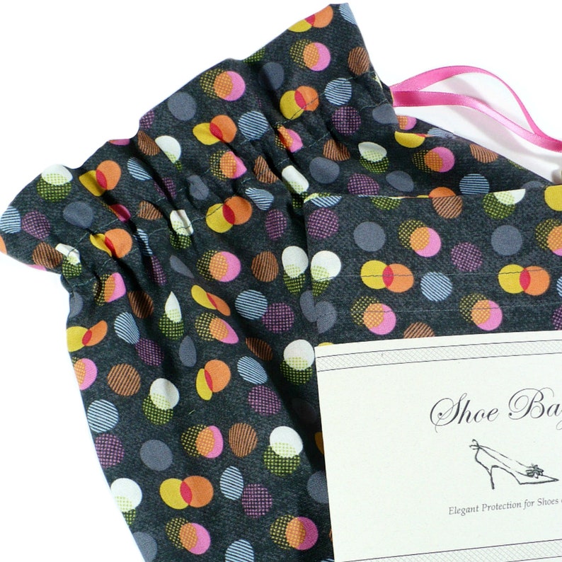 May include: A black fabric shoe bag with a drawstring closure. The bag is decorated with colorful polka dots and has a white tag that reads "Shoe Bag Elegant Protection for Shoes".