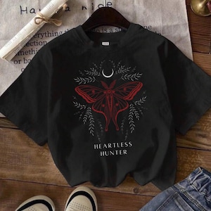 May include: Black t-shirt with a red and white moth graphic and the text "Heartless Hunter".