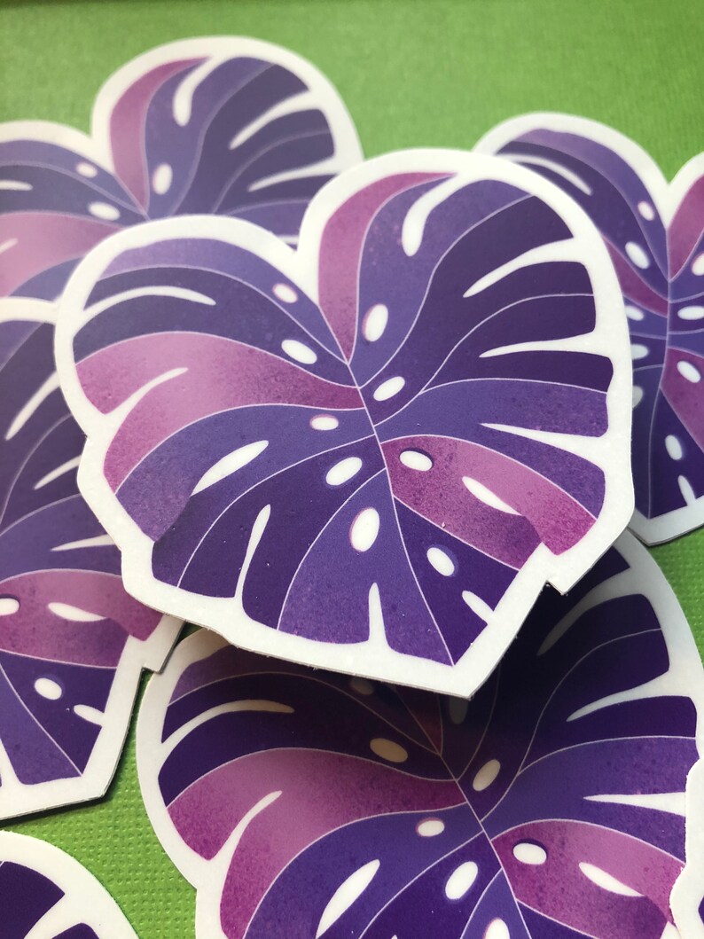 May include: Purple and pink monstera leaf stickers with white outlines. The stickers are stacked on top of each other.