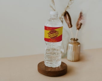 May include: A clear plastic bottle with a red and yellow label that says "Medicated Rusteze" and "Medicated Vapor Ointment". The bottle is sitting on a wooden coaster.