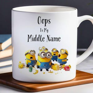 Puede incluir: Taza de café de cerámica blanca con un gráfico en blanco y negro de los Minions de la película Gru, mi villano favorito. El texto "Oops Is My Middle Name" está impreso en la taza.