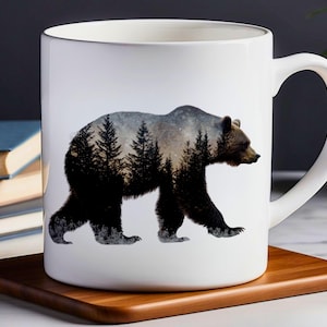 Könnte beinhalten: Weiße Keramiktasse mit einer schwarzen Bärensilhouette. Der Bär geht durch eine Waldszene mit einem Sternenhimmel im Hintergrund.