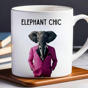 May include: White ceramic mug with a black handle. The mug has a graphic of an elephant wearing a pink suit and a black bow tie. The text "ELEPHANT CHIC" is printed in black at the top of the mug.