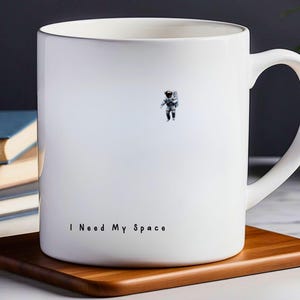 May include: White ceramic mug with a small astronaut graphic and the text "I Need My Space".