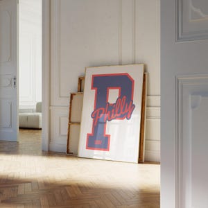 Könnte beinhalten: Ein gerahmter Druck mit einem großen blauen Buchstaben "P" und dem Wort "Philly" in roter Kursivschrift. Der Buchstabe "P" hat einen roten Umriss und das Jahr "1982" ist unten in Rot gedruckt.