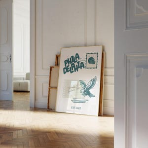 May include: A framed print with a green and white design. The print features the words "Philadelphia" and a graphic of an eagle with a football helmet. The print also includes the text "EST. 1682".