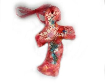 Puede incluir: Una cruz de cerámica rosa con un diseño de mosaico blanco y azul. La cruz tiene una cinta roja atada a la parte superior.